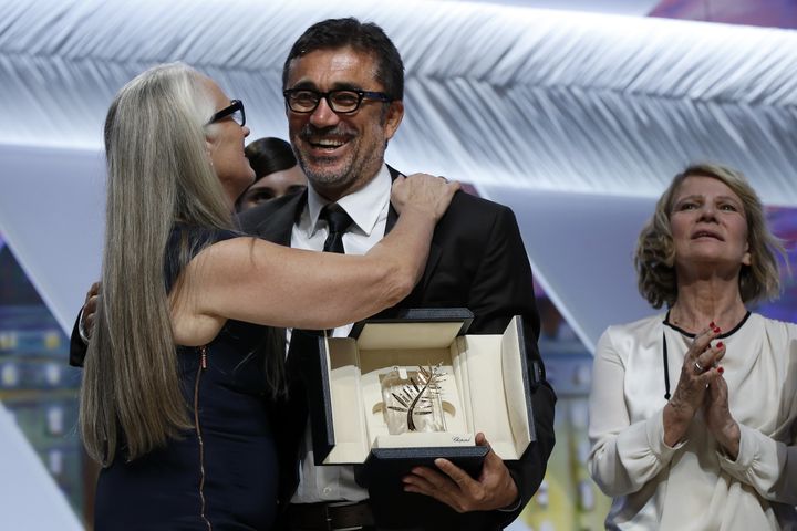 Le réalisateur turc Nuri Bilge Ceylan, félicité par la présidente du jury, Jane Campion, après avoir reçu la palme d'or pour "Winter sleep" à Cannes en 2014. (VALERY HACHE / AFP)