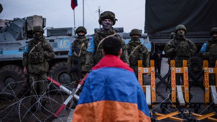 Un manifestant arménien se tient devant des soldats russes qui bloquent la route à l'extérieur de Stepanakert, capitale de la région du Haut-Karabakh que se dispute l'Arménie et l'Azerbaïdjan, le 24 décembre 2022. Photo d'illustration. (DAVIT GHAHRAMANYAN / AFP)