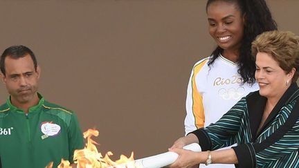 La présidente Dilma Rousseff remet la flamme olympique à la joueuse de volley-ball brésilienne Fabiana Claudino, le 3 mai 2016, au Palais du Planalto à Brasilia. (EVARISTO SA / AFP)