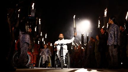 Michaël Jérémiasz porte la flamme lors de la cérémonie d'ouverture des Jeux paralympiques de Paris, le 28 août 2024. (GONZALO FUENTES / AFP)