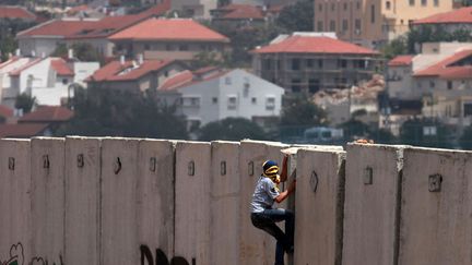 Un Palestinien escalade le mur qui s&eacute;pare Isra&euml;l de Nilin (Cisjordanie), le 14 juin 2013. (ABBAS MOMANI / AFP)