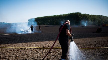 Des pompiers éteignent un feu déclenché par un tracteur dans un champ à Sainghin-en-Weppes (Nord), le 18 juillet 2022. (MAXPPP)