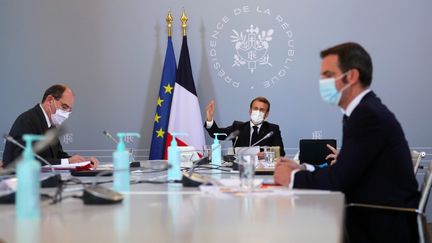 Le président Emmanuel Macron (milieu), avec le ministre de la Santé Olivier Véran (droite) et le Premier ministre Jean Castex, lors d'un Conseil de défense sanitaire, le 12 novembre 2020 à l'Elysée. (THIBAULT CAMUS / AFP)