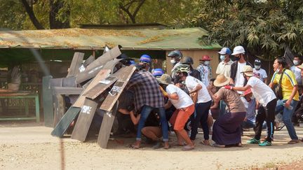 Des manifestants se réfugient derrière des boucliers pour se protéger face aux forces de l'ordre, le 7 mars 2021 à Bagan (Birmanie). (AFP)