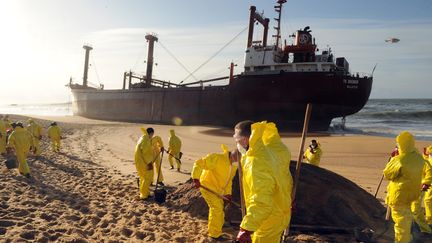 Des pompiers nettoient la plage de Kerminihy, alors que le cargo &eacute;chou&eacute; a perdu des dizaines de tonnes de carburant, le 17 d&eacute;cembre 2011 &agrave; Erdeven. (FRED TANNEAU /&nbsp;AFP PHOTO)