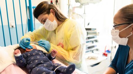 Des soignantes au&nbsp;chevet d'un enfant atteint de bronchiolite à Bry-sur-Marne, le 8 décembre 2021. (ALINE MORCILLO / HANS LUCAS / VIA AFP)