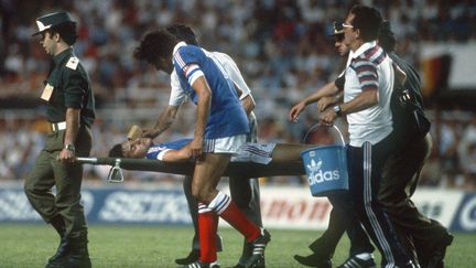 Le d&eacute;fenseur Patrick Battiston est &eacute;vacu&eacute; apr&egrave;s avoir &eacute;t&eacute; heurt&eacute; de plein fouet par le gardien allemand Harald Schumacher, le 8 juillet 1982 &agrave; S&eacute;ville (Espagne). (STAFF / AFP)