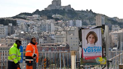 Deux personnes passent près d'une affiche de la candidate Les Républicains pour la mairie à Marseille, Martine Vassal, le&nbsp;21 janvier 2020. (GERARD JULIEN / AFP)