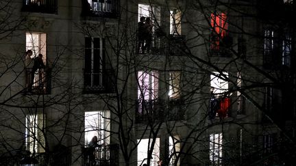 Des Parisiens applaudissent depuis leur balcon à 20h, le 18 mars 2020, en hommage aux soignants mobilisés dans la lutte contre le coronavirus. (THOMAS COEX / AFP)