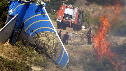 Des pompiers &eacute;teignent l'incendie provoqu&eacute; par le crash d'un Boeing 737 de Helios Airways,&nbsp;le 14 ao&ucirc;t 2005, pr&egrave;s d'Ath&egrave;nes (Gr&egrave;ce). (LOUISA GOULIAMAKI / AFP)