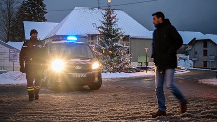 Un homme passe devant un véhicule de gendarmerie situé à Mignovillard (Jura), à proximité des lieux où des débris du Mirage 2000D disparu ont été retrouvés, mercredi 9 janvier 2019. (FABRICE COFFRINI / AFP)