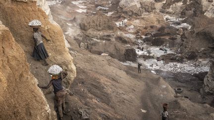 Chaussés parfois de simples tongs avec des charges de roche de plusieurs kilos sur la tête, tous effectuent plusieurs allers-retours dans la journée sur un étroit chemin escarpé. (JOHN WESSELS / AFP)