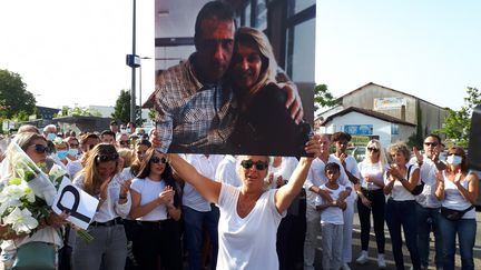 Véronique Monguillot brandit une photo de son couple lors du départ de la marche blanche en hommage à son époux, Philippe, chauffeur de bus agressé à Bayonne (Pyrénées-Atlantiques), 8 juillet 2020. (CÉLINE ARNAL / FRANCE-BLEU PAYS BASQUE)