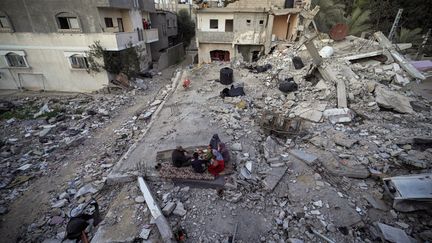 Une famille palestinienne au moment de la rupture du jeûne, au milieu des ruines de leur maison familiale, à Deir el-Balah, dans le centre de la bande de Gaza, le 11 mars 2024. (- / AFP)