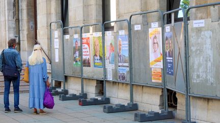 Des passants s'arrêtent devant les affiches des candidats aux élections dans la région Auvergne-Rhône-Alpes, le 31 mai 2021, à Valence (Drôme). (NICOLAS GUYONNET / HANS LUCAS / AFP)