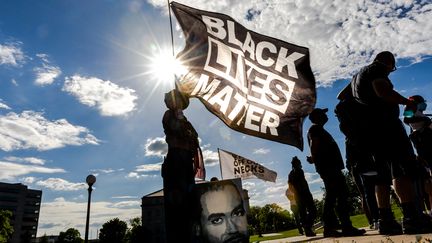 Une femme tient un drapeau Black Lives Matter lors d'une manifestation en souvenir de George Floyd, le 24 mai 2021 à Saint Paul, Minnesota. (KEREM YUCEL / AFP)