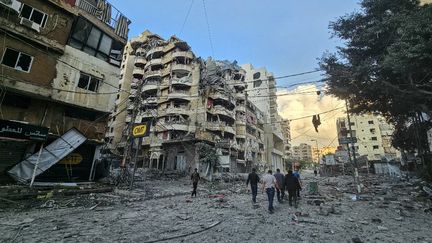 Des gens marchent au milieu des destructions, à la suite des frappes aériennes israéliennes qui ont ciblé le quartier de Haret Hreik, dans la banlieue sud de Beyrouth (Liban), le 16 novembre 2024. (AFP)