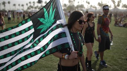 Une jeune femme avec un drapeau sur lequel figure des feuilles de cannabis, au festival de Coachella &agrave; Indio (Californie, Etats-Unis), le 12 avril 2014. (DAVID MCNEW / AFP)