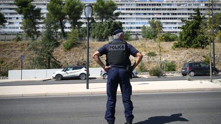 Un policier se tient devant un bâtiment du quartier Pissevin, à Nîmes, là où a eu lieu la fusillade qui a fait un mort, dans la nuit du 21 au 22 août 2023. (NICOLAS TUCAT / AFP)