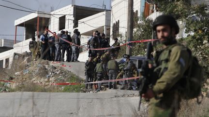 Des soldats israéliens sur le site d'une attaque à la voiture bélier, oeuvre d'un Palestinien, le 27 novembre 2015 à Beit Oummar, en Cisjordanie. (HAZEM BADER / AFP)