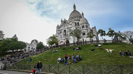 Des gens sont assis sur la pelouse devant la basilique du Sacré-Cœur à Paris, le 12 mai 2020 (photo d'illustration). (BERTRAND GUAY / AFP)