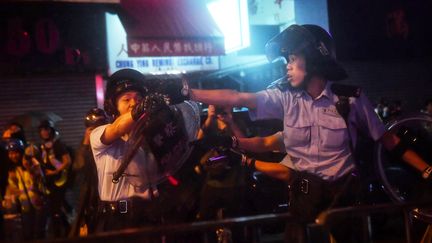 Un policier pointe une arme à feu lors d'une manifestation à Hong Kong, le 25 août 2019. (LILLIAN SUWANRUMPHA / AFP)