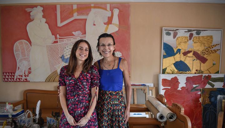 Mariza et Viktoria Fassianou, la femme et la fille d'Alekos Fassianos, posent dans leur maison près d'Athènes devant des oeuvres de l'artiste grec&nbsp;(29 septembre 2021). (LOUISA GOULIAMAKI / AFP)