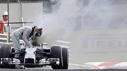 Le pilote britannique Lewis Hamilton s'extrait de sa voiture en flammes sur le circuit du GP de Hongrie (DARKO BANDIC / POOL)