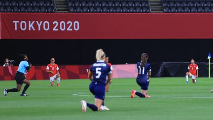 Les footballeuses britanniques (en bleu) et chiliennes (en rouge) s'agenouillent avant le début de leur match à Sapporo, le 21 juillet 2021. (TAKUYA MATSUMOTO / YOMIURI / AFP)