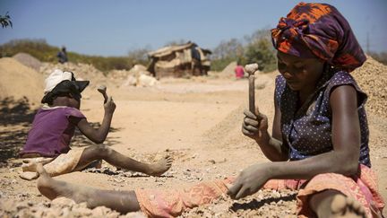 Une femme et un enfant&nbsp;cassent de la roche extraite&nbsp;d'une mine de cobalt à Lubumbashi,&nbsp;dans la province du Katanga, en RDC, le 23 mai 2016. (JUNIOR KANNAH / AFP)