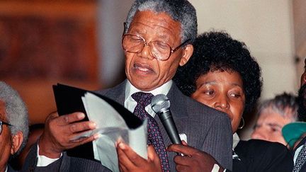 du monde entier et une foule immense, Nelson Mandela chaussant les lunettes de sa femme Winnie (de laquelle il divorce en 1992) délivre son premier discours d’homme libre au Cap, le 11 février 1990. 
 
«Friends, comrades and fellow South Africans.
I greet you all in the name of peace, democracy and freedom for all
…» (AFP/WALTER DHALDHLA)