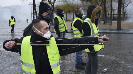 Un membre des "giles jaunes" armé d'une fronde fait face aux forces de l'ordre près des Champs-Elysées à Paris le samedi 1er décembre 2018. (LUCAS BARIOULET / AFP)