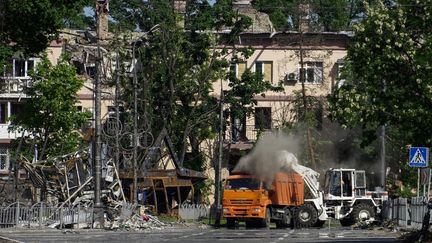 Des ouvriers nettoient des débris dans une rue de Marioupol, en Ukraine, le 1er juin 2022. (STRINGER / AFP)