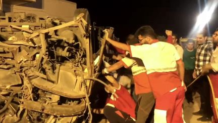 Des membres du Croissant-Rouge iranien inspectant la carcasse d'un bus près de Taft, dans la province de Yazd, dans le centre de l'Iran, le 21 août 2024. (IRIB / HANDOUT / MAXPPP)