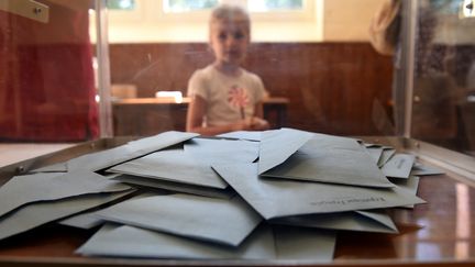 Un enfant derrière une urne &nbsp;dans un bureau de vote d'Authon, dans le Nord de la France.&nbsp; (GUILLAUME SOUVANT / AFP)