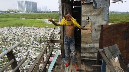 Un jeune gar&ccedil;on remet son tee-shirt en sortant de toilettes publiques install&eacute;es dans un bidonville de Djakarta (Indon&eacute;sie), le 22 f&eacute;vrier 2012. (BEAWIHARTA / REUTERS)