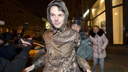 Un policier arr&ecirc;te un jeune homme qui manifestait sur la place Triumphalna&iuml;a, &agrave; Moscou, le 7 d&eacute;cembre. (ILIYA PITALEV/AFP)