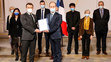 Emmanuel Macron (à g.) et l'historien Vincent Duclert (à dr.), lors de la remise du rapport sur le rôle de la France dans le génocide du Rwanda, le 26 mars 2021, à l'Elysée. (LUDOVIC MARIN / AFP)