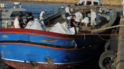 1er Juillet 2014.Dans le port sicilien de Pozzallo, des sauveteurs sortent les corps des 45 migrants morts dans la cale de ce bateau d'à peine 20 mètres de long qui transportait 611 migrants. La marine italienne en a sauvé 566. (GIOVANNI ISOLINO / AFP)