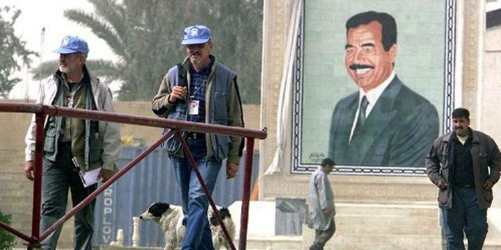 Inspecteurs de l'ONU (à gauche) marchant près d'un portrait de Saddam Hussein sur le site de Ibn al-Haitham (20 km au nord de Bagdad) le 20-2-2003). (AFP - Ahmed Al-Rubye)