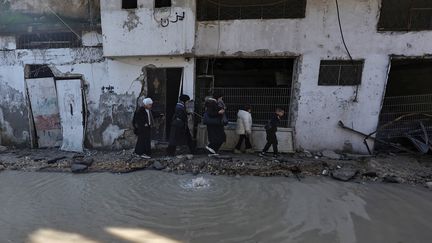 A Palestinian family walks along a flooded street in the refugee camp in Tulkarem, where the Israeli army carried out night raids, on January 19, 2024. (ZAIN JAAFAR / AFP)