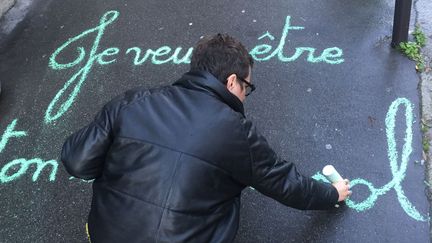 Claudie, alias la street artiste Achbé, "craieant" un de ses messages sur un trottoir de Montmartre en janvier 2018.
 (Laure Narlian / Culturebox)