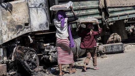 Des personnes passent devant un camion militaire endommagé à Hayk, en Éthiopie, le 13 décembre 2021. (AMANUEL SILESHI / AFP)