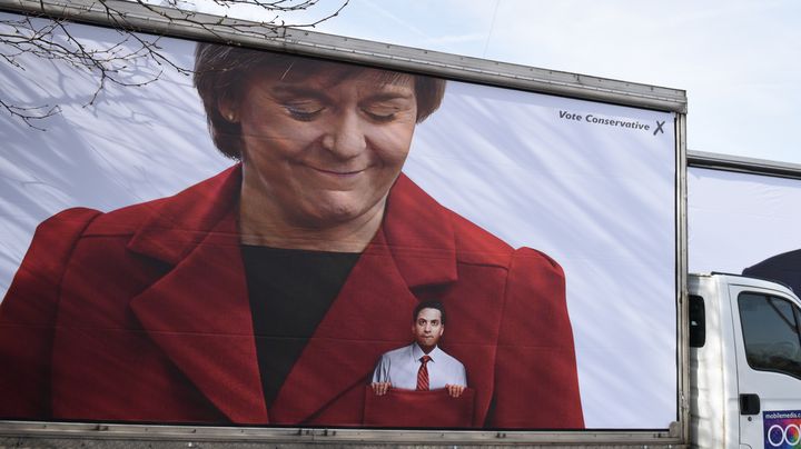 Une affiche du parti conservateur montrant Nicola Sturgeon, leader du SNP, et Ed Miliband, chef de file des travaillistes, dans la poche de sa veste.&nbsp; (OLI SCARFF / AFP)