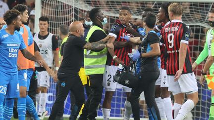 Des supporters niçois ont envahi le terrain et en sont venus aux mains avec les joueurs marseillais., le 22 août 2021. (VALERY HACHE / AFP)