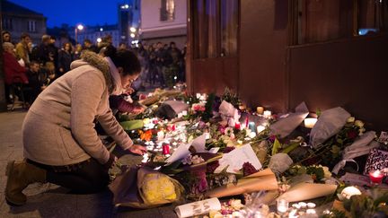 Une femme allume une bougie en face du café Carillon à Paris, le 14 novembre 2015.&nbsp; (MARIUS BECKER / DPA / AFP)