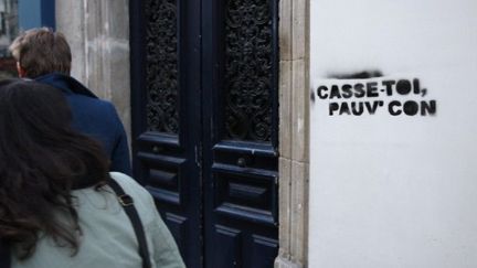 Des personnes passent devant une inscription sur le mur d'un immeuble parisien (archives) (AFP PHOTO / PATRICK KOVARIK)