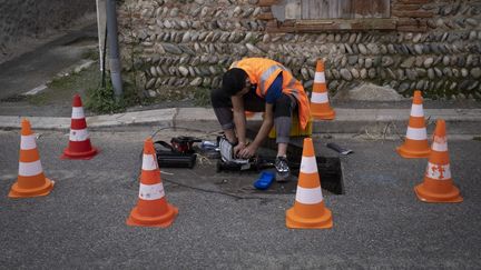 Un technicien installe la fibre optique dans un quartier de Toulouse, le 20 octobre 2021. (ARNAUD CHOCHON / HANS LUCAS / AFP)