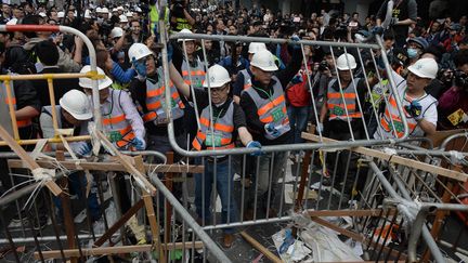 Des employ&eacute;s d&eacute;montent les barricades des manifestants prod&eacute;mocratie, le 11 d&eacute;cembre 2014, &agrave; Hong Kong. (DALE DE LA REY / AFP)