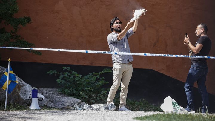 Salwan Momika brûle des pages d'un coran lors de sa première action, devant la grande mosquée de Stockholm (Suède), le 28 juin 2023. (STEFAN JERREVANG / TT NEWS AGENCY / AFP)